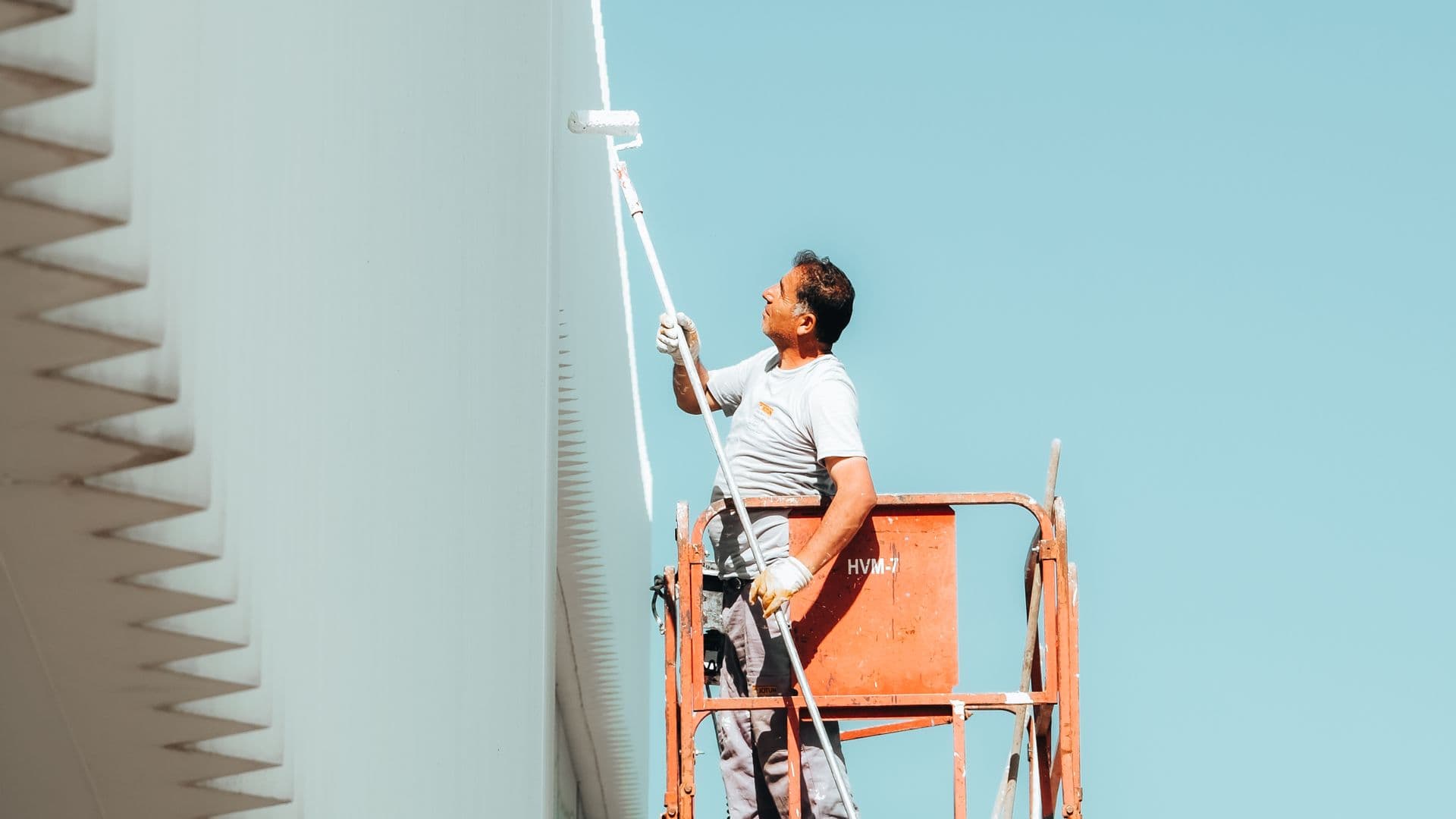 Professional painter on cherry picker painting a building exterior